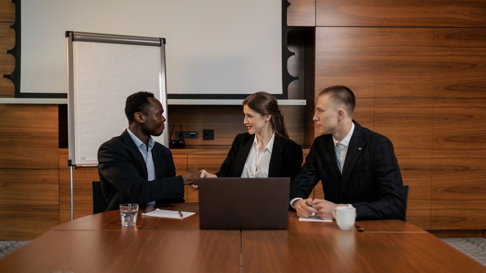 Students and professionals celebrating exam preparation progress in a warm corporate meeting room